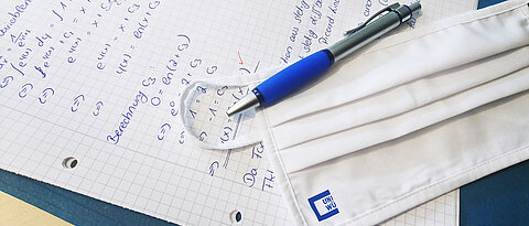 Mouth and nose protection is lying with a pen on an exam sheet